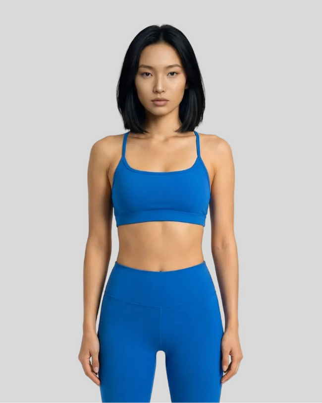 Model wearing a blue  LumaForm Crisscross sports bra and leggings on a light gray background