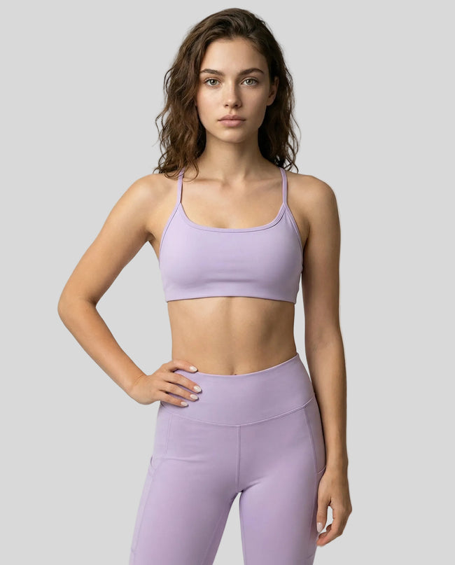 Model wearing a lilac LumaForm Crisscross sports bra and leggings on a light gray background