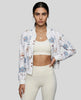 Woman wearing floral zip-up jacket layered over activewear leggings in an elevated casual look