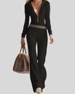 Mid body front view of woman wearing Monaco Hooded Jumpsuit in Black, showing ribbed texture, striped waistband and zip-front design