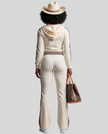 Full body back view of woman wearing Monaco Hooded Jumpsuit in Milky White showing hood and contrast stripe details