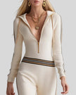 Upper body front view of woman wearing Monaco Hooded Jumpsuit in Milky White with zip neckline and contrast sleeve stripes