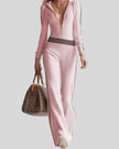 Mid body front view of woman wearing Monaco Hooded Jumpsuit in Pink, showing ribbed texture, striped waistband and zip-front design