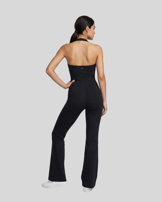 Back view of a model wearing the MotionFlow Halter Jumpsuit in Black