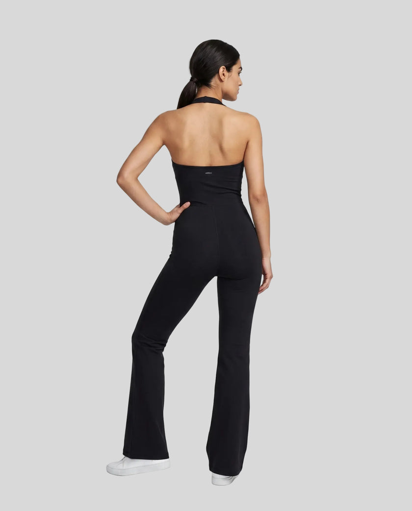 Back view of a model wearing the MotionFlow Halter Jumpsuit in Black