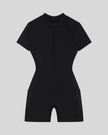 MotionFlow Romper in Black front view featuring a mock neck, quarter-zip front, and bermuda-length shorts