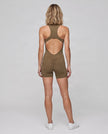 Full body back view of model wearing the MotionFlow Yoga Romper in Coffee.
