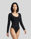 Model wearing the Athlesi MotionForm Long Sleeve Bodysuit in Black, angled front view showing the streamlined second-skin fit