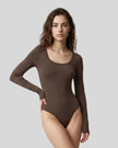 Model wearing the Athlesi MotionForm Long Sleeve Bodysuit in Coffee, front view highlighting the U-neckline and fitted silhouette