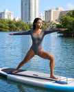 Model wearing the Athlesi MotionForm Long Sleeve Bodysuit in Gray during a yoga pose, showing its flexible body-contouring fit