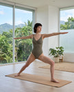 Woman wearing the MotionZip Ruched Bodysuit in Gray during a yoga pose, showing its flexible second-skin fit