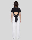 Full body back view of woman wearing Nova Tie-Back Tee with open-back cutout and Black bow