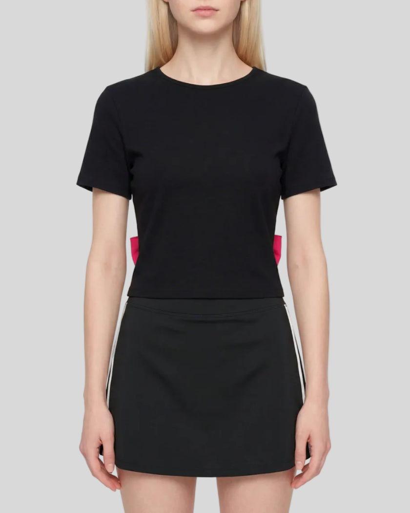 Upper body front view of woman wearing Nova Tie-Back Tee in black and rose red with a fitted cropped silhouette