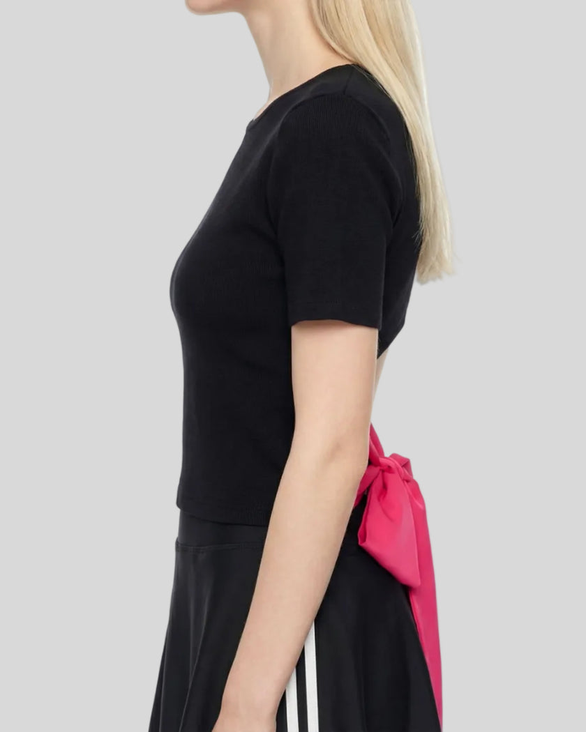 Upper body side view of woman wearing Nova Tie-Back Tee showing fitted silhouette and open-back design