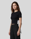Angled upper body front view of woman wearing Nova Tie-Back Tee in black with contrasting White tie detail