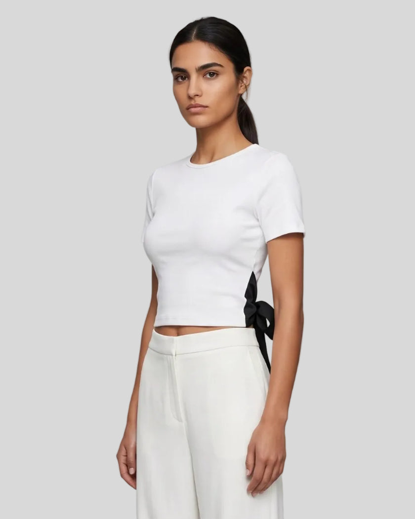Angled upper body front view of woman wearing Nova Tie-Back Tee in white with contrasting Black tie detail
