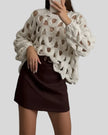 Open-weave cable knit sweater in white showing subtle sheerness, front angle