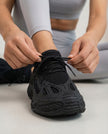 Woman adjusting black Pulseform Mesh Sneakers showing fit and breathable mesh upper detail