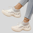 White mesh sneakers side view showing sculpted sole and breathable upper design