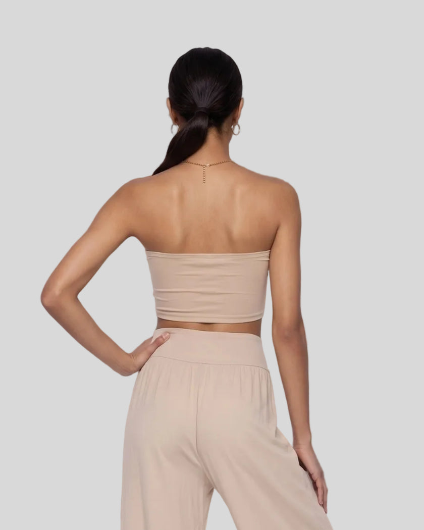 Model wearing the Athlesi QuietForm Ruched Tube Top in Pale Khaki, mid-body back view showing the clean strapless silhouette.