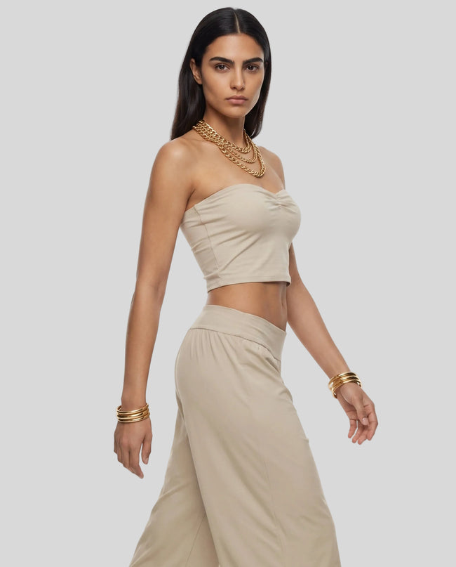 Model wearing the Athlesi QuietForm Ruched Tube Top in Pale Khaki, angled side view highlighting the ruched neckline and cropped fit.