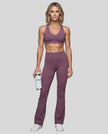 Full body front view of woman wearing Sculpt Halter Sports Bra with matching yoga pants in plum purple