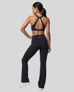 Back view of a woman modeling a black Athlesi activewear set consisting of a Sculpt Yoga Pants and matching Sculpt Halter Sports Bra