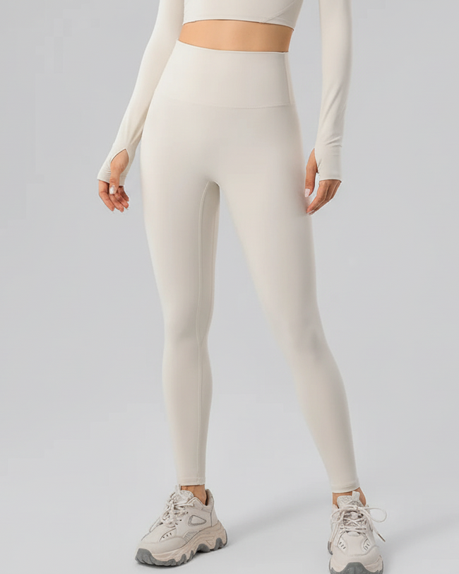 Person wearing beige leggings and a long-sleeve top on a light gray background
