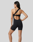 Model wearing Athlesi SculptLine one-shoulder active romper in black, lifestyle back view showing open back