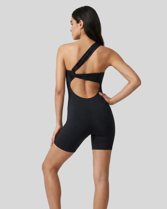 Model wearing Athlesi SculptLine one-shoulder active romper in black, lifestyle back view showing open back