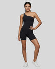 Model wearing Athlesi SculptLine one-shoulder active romper in black, lifestyle front view