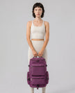 Model carrying ShiftForm Carry Pack in plum purple styled for gym and everyday movements