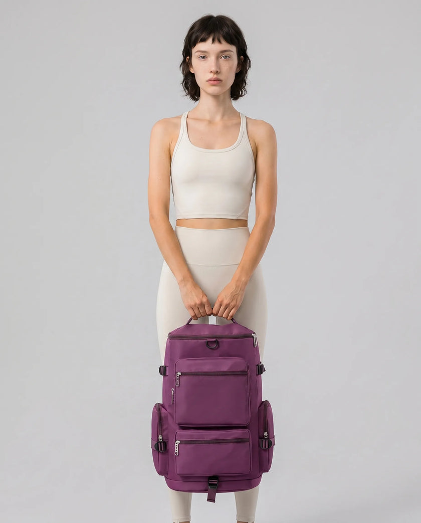 Model carrying ShiftForm Carry Pack in plum purple styled for gym and everyday movements