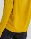 Close-up of Athlesi SoftFlow soft stretch fabric lower hem & stitching in mustard