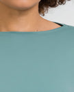 Close-up of Athlesi SoftFlow soft stretch fabric, neck hem & stitching in teal