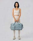 Model holding SoftForm Carry Bag in air force blue styled for everyday and gym movement