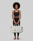 Model holding SoftForm Carry Bag in beige styled for everyday and gym movement