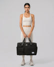 Model holding SoftForm Carry Bag in black styled for everyday and gym movement