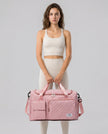 Model holding SoftForm Carry Bag in dusty pink styled for everyday and gym movement