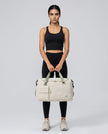 Model holding SoftForm Carry Bag in white styled for everyday and gym movement