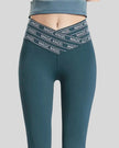 Front view of Statement Angel Legging in deep teal with slogan waistband