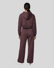 Full body back view of woman wearing Dark Reddish Purple StudioEase Cropped Hoodie with matching sweatpants.