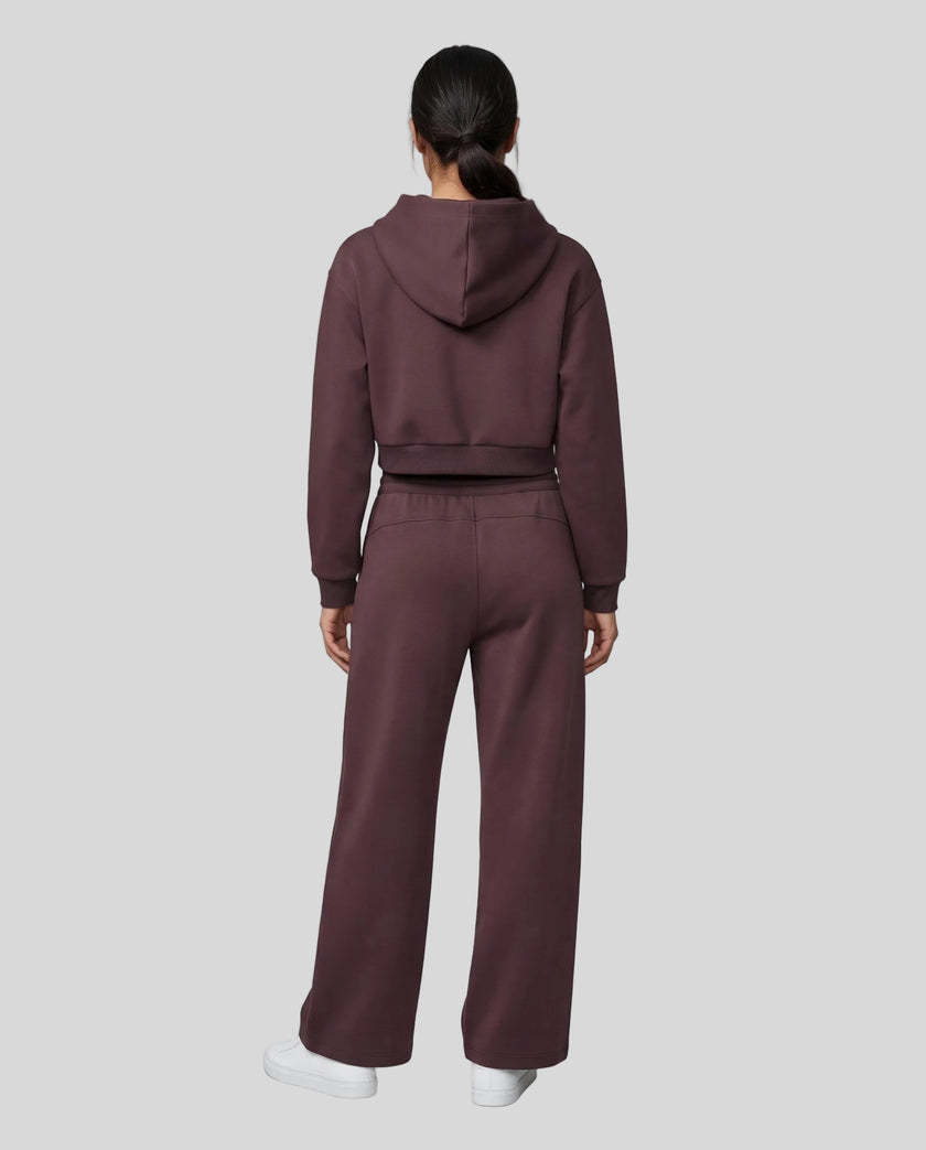 Full body back view of woman wearing Dark Reddish Purple StudioEase Cropped Hoodie with matching sweatpants.