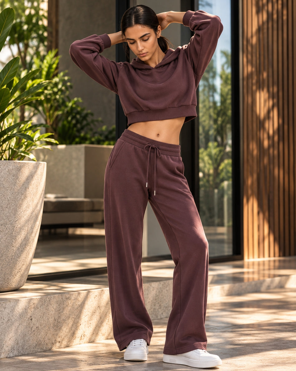 Front view of woman standing on a terrace, wearing Dark Reddish Purple StudioEase Cropped Hoodie with matching sweatpants.
