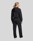 Full body back view of woman wearing black StudioEase Cropped Zip Hoodie in a coordinated casual outfit