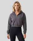 Upper body front view of woman wearing StudioEase Cropped Zip Hoodie zipped closed in Charcoal Gray