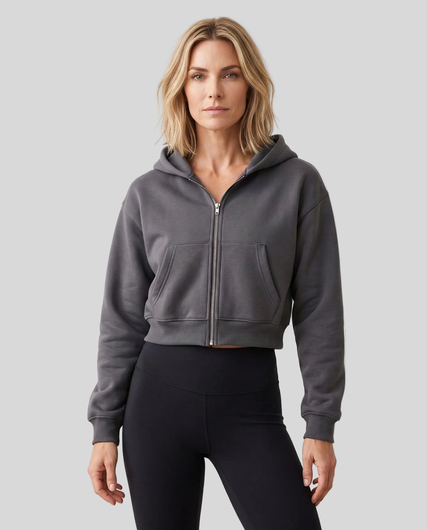 Upper body front view of woman wearing StudioEase Cropped Zip Hoodie zipped closed in Charcoal Gray