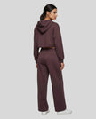 Full body back view of woman wearing dark reddish purple StudioEase Cropped Zip Hoodie in a coordinated casual outfit