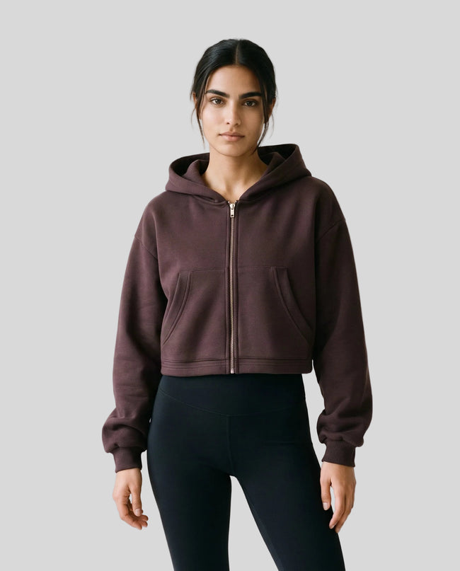 Upper body front view of woman wearing StudioEase Cropped Zip Hoodie zipped closed in Dark Reddish Purple