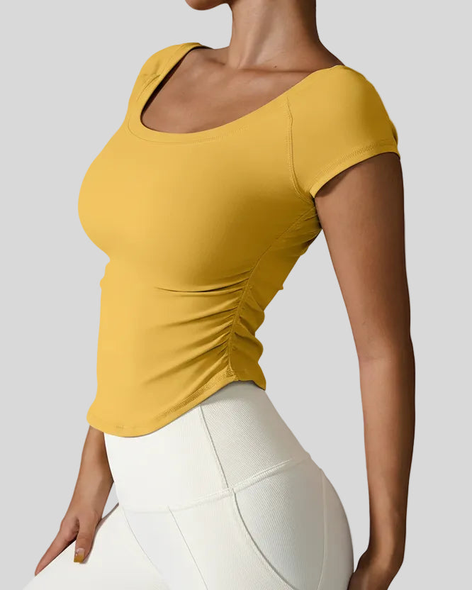 Side view of StudioFlow Short Sleeve Active Top in mustard showing rouching detail